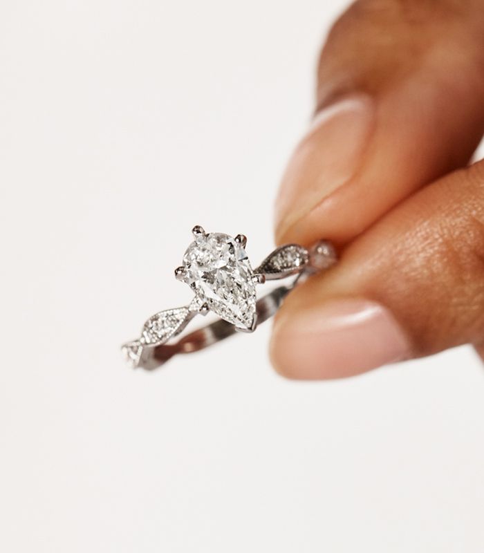 Woman Holding A Pave Engagement Ring Between Fingers