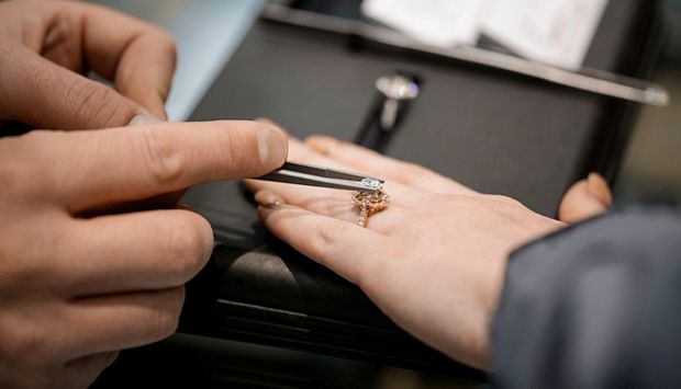 A jewelry consultant places a new center stone in an engagement ring