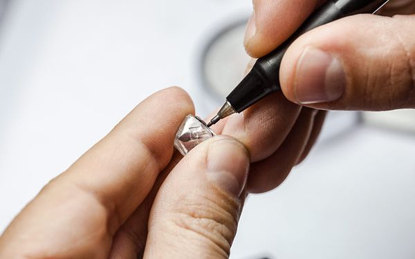 Person Using Tool To Cut Loose Diamond