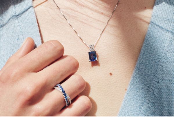 Mobile Image of a woman wearing a blue gemstone pendant and fashion band