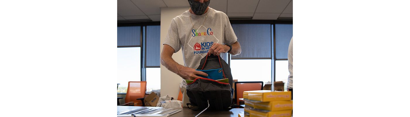 A Shane Co. employee packing a backpack with school supplies