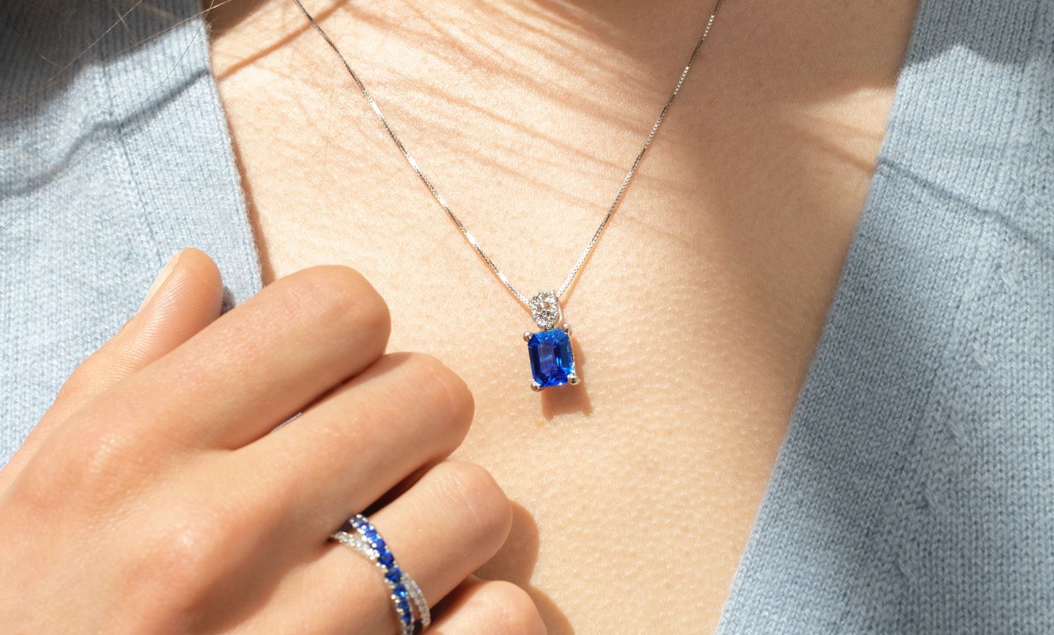 A women wearing a blue gemstone fashion ring and matching pendant