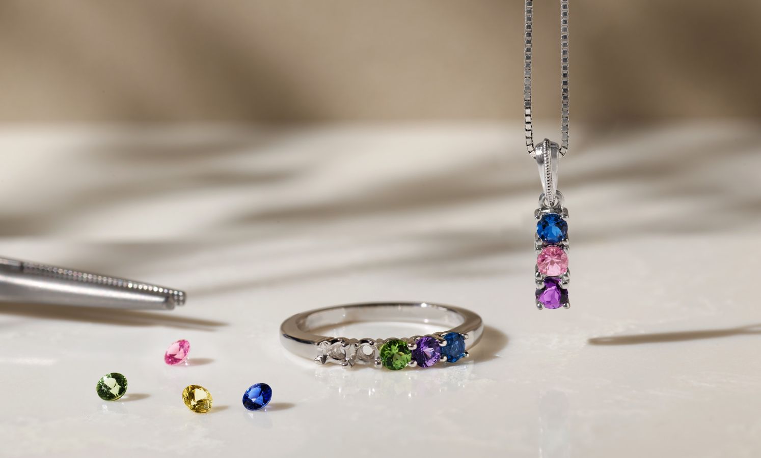 A collection of loose gemstones being set into a ring and pendant