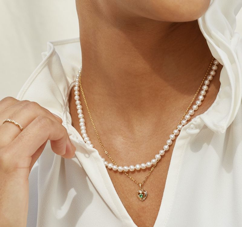 A woman wearing a fashion pendant and pearl strand necklace
