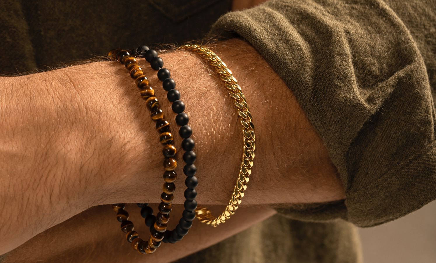 A man wearing three bracelets of different styles