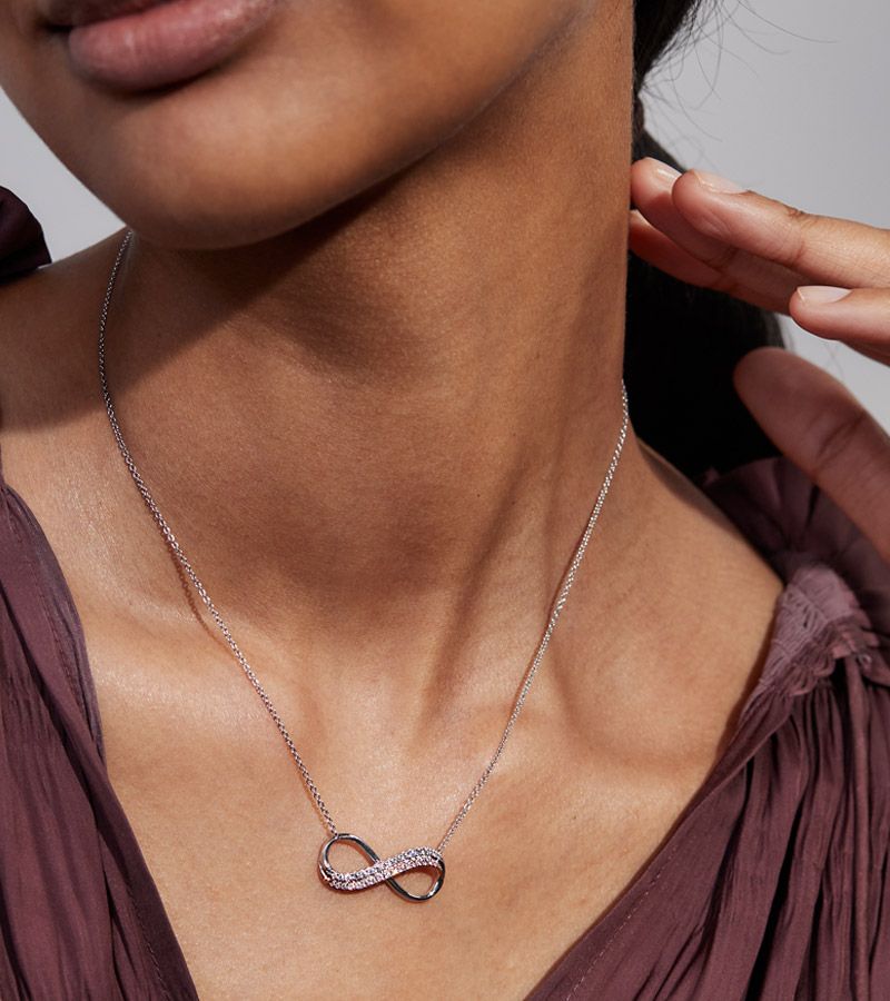 A woman wearing a diamond infinity symbol necklace