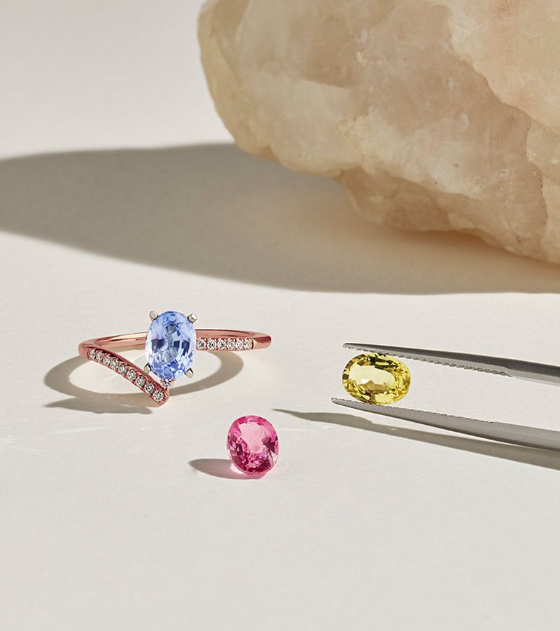 A fashion ring with a gemstone center stone and two loose gemstones next to it