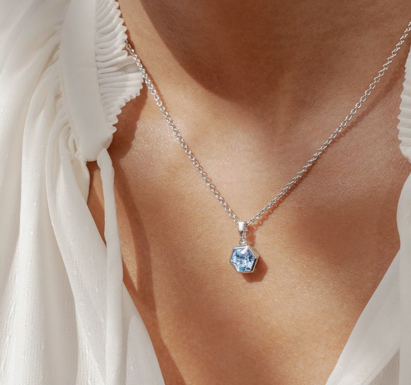 Woman wearing a pendant necklace with a blue gemstone