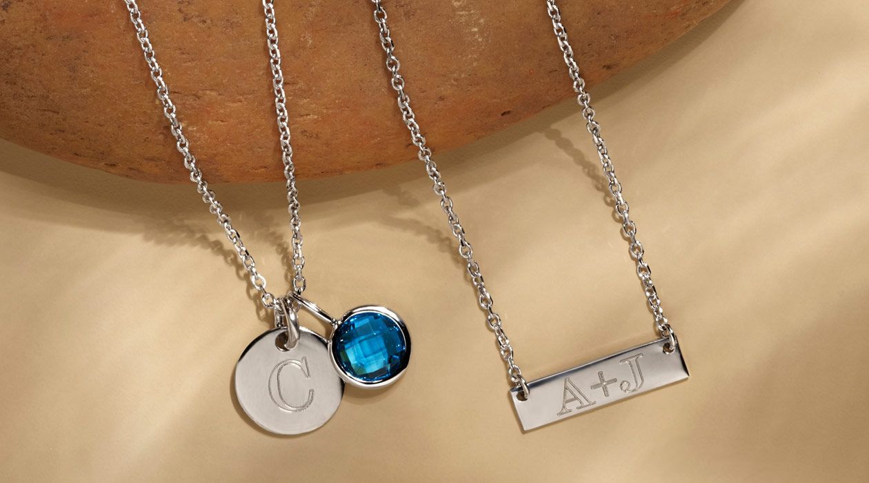 An engraved circle pendant with gemstone charm and an engraved bar necklace