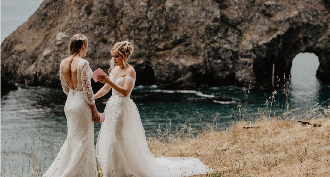Two brides reading their vows to each other