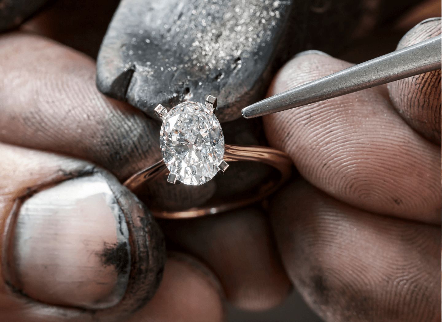 A jeweler's hands working on a solitaire diamond engagement ring