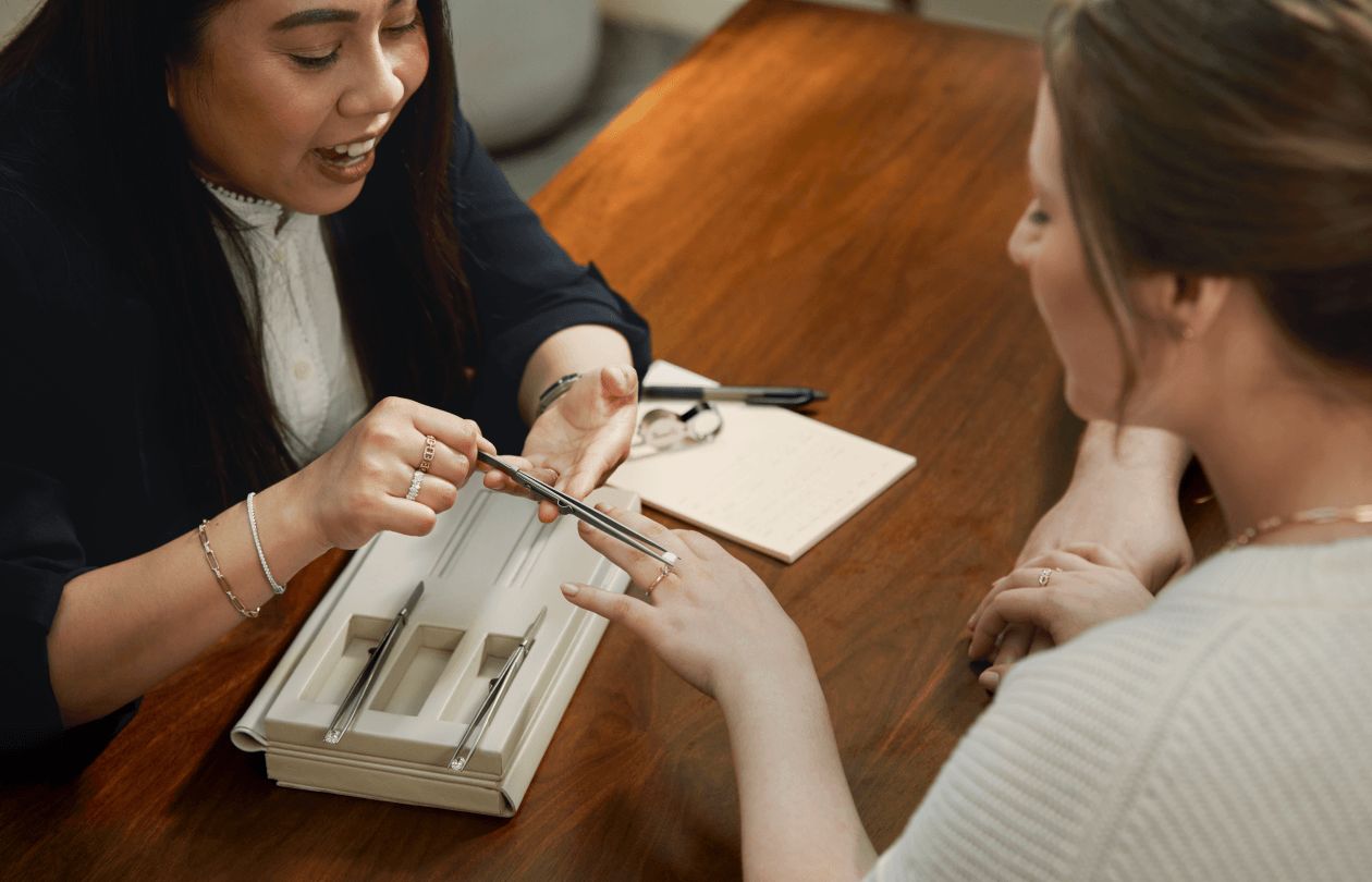 A jewelry consultant showing a customer a diamond in an engagement ring
