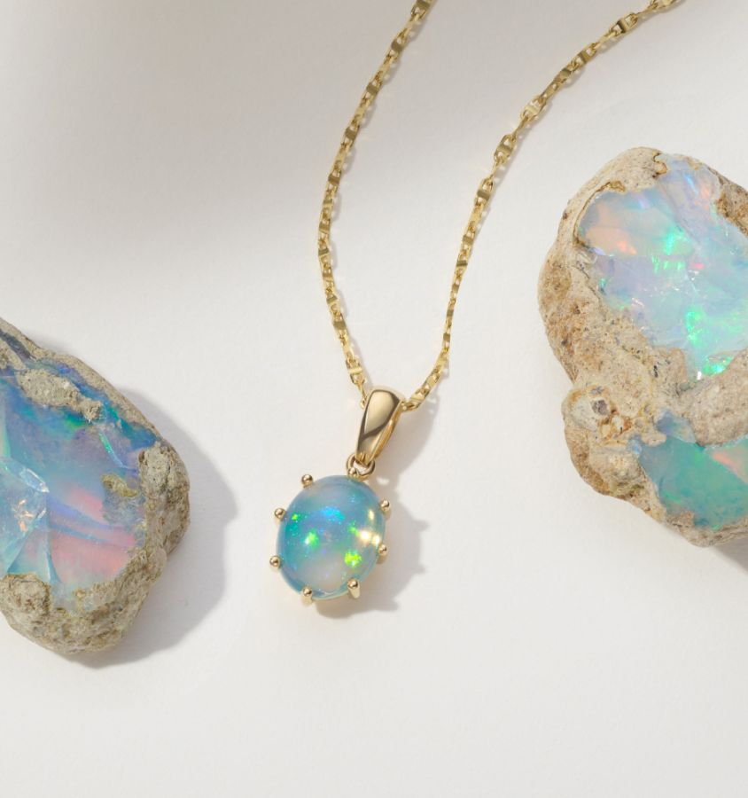 An opal pendant next to two raw opals