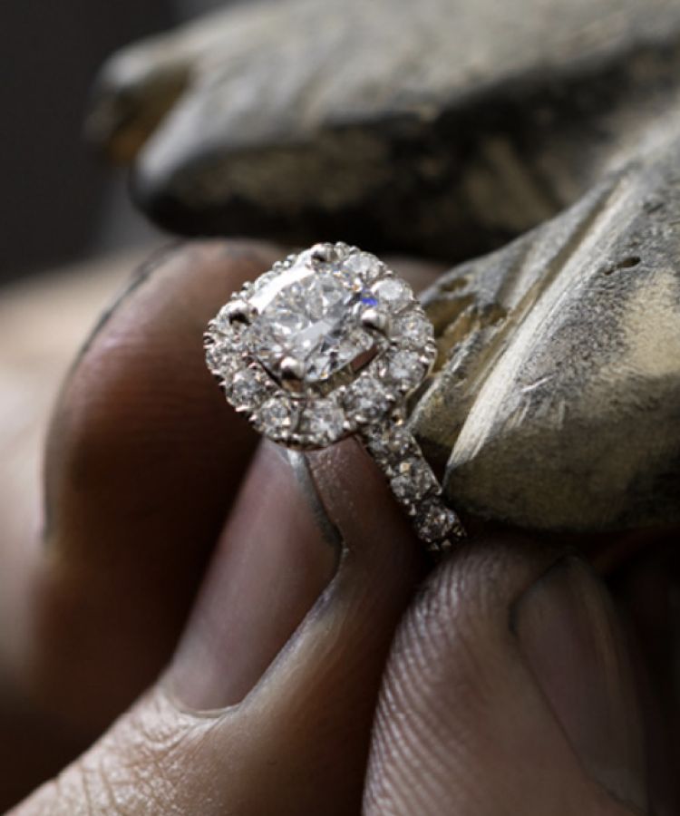 A jeweler's hands holding a diamond engagement ring