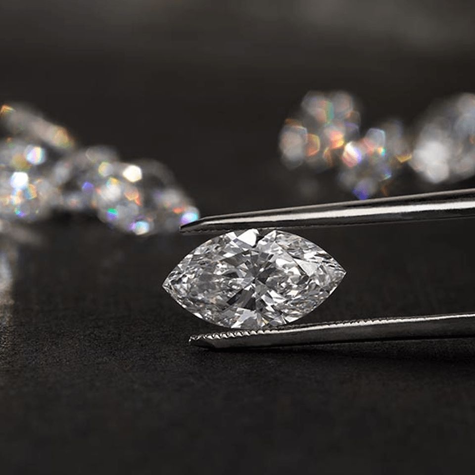 A lab grown marquise diamond held between tweezers.
