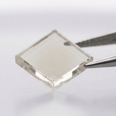 A lab grown diamond seed being held by tweezers