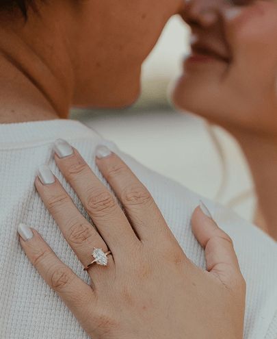 A couple embracing and showing the woman's engagement ring setting.