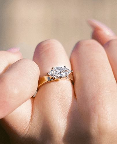 A woman showing off an east west setting engagement ring