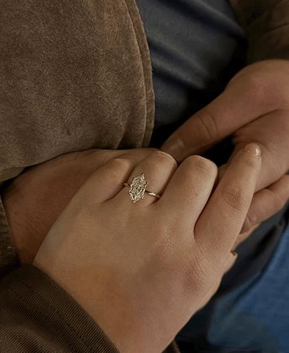 A couple holding hands and showing off a lab grown marquise engagement ring