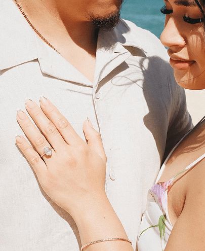 A couple posing together, showing off the woman's engagement ring