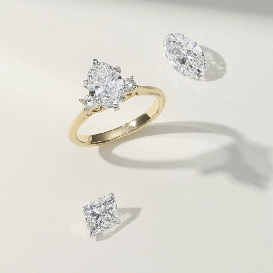 A diamond engagement ring with a Shane Classic oval center stone surrounded by two other loose Shane Classic diamonds