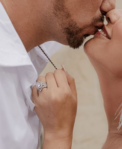 A couple kissing and showing off a diamond engagement ring