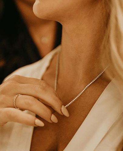 A woman wearing a diamond tennis necklace and a diamond band