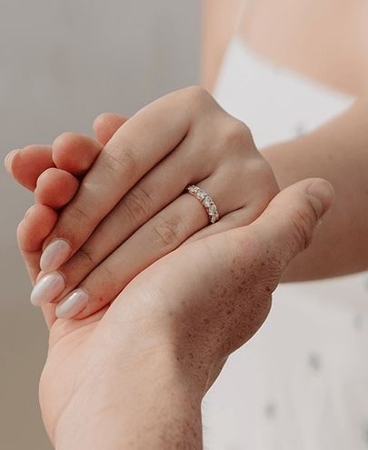 A couple holding hands and showing a diamond wedding band