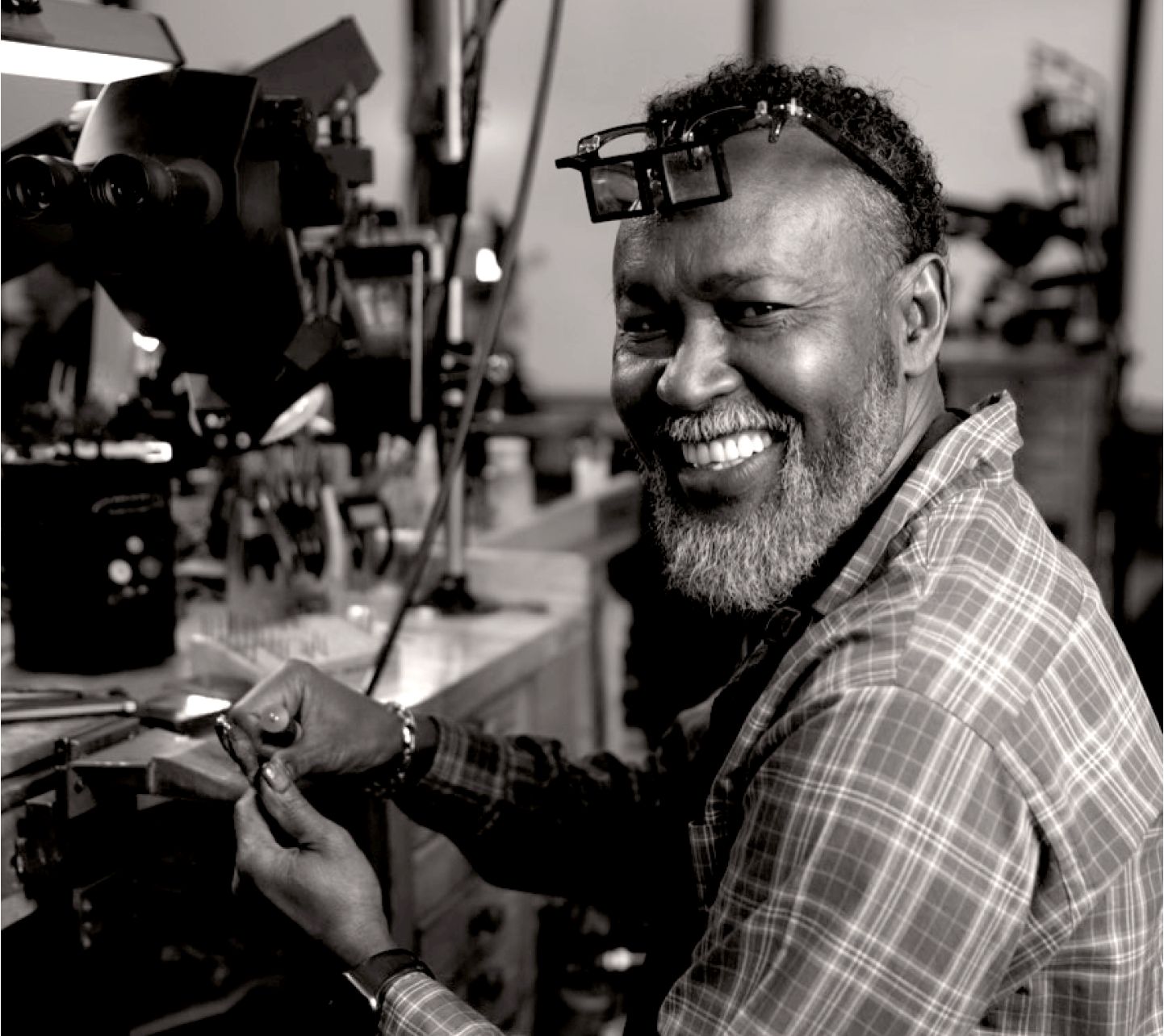 A smiling jeweler working at their bench