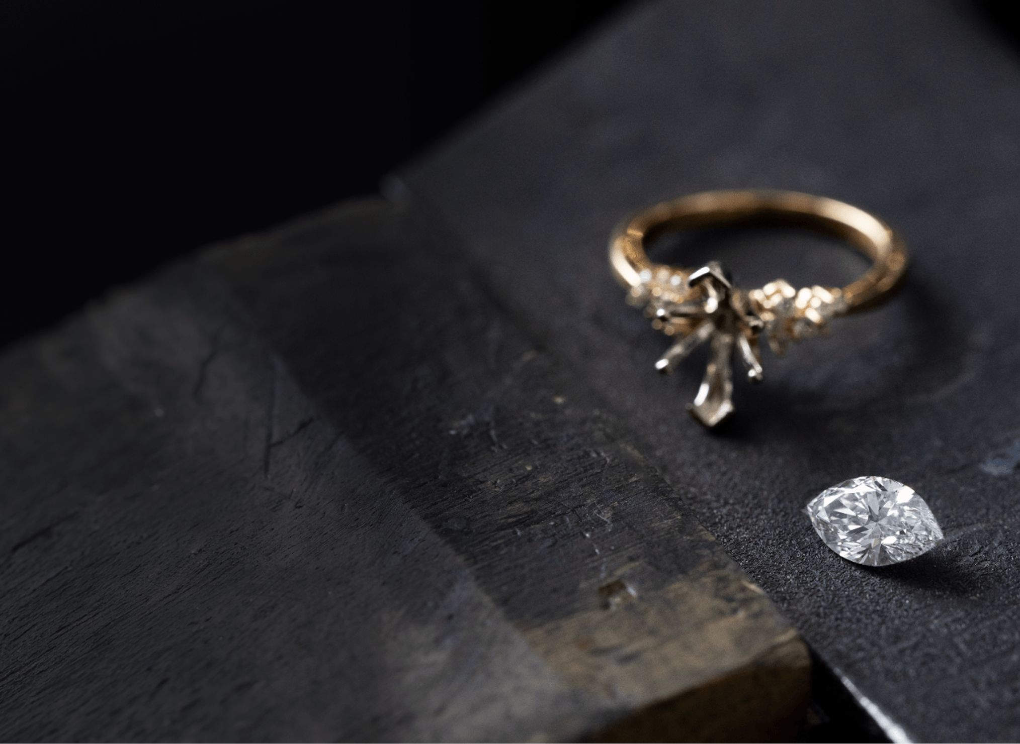 An engagement ring with a loose marquise diamond center stone next to it
