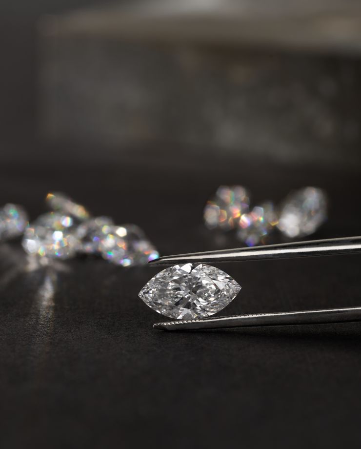 A marquise diamond being held between a pair of tweezers