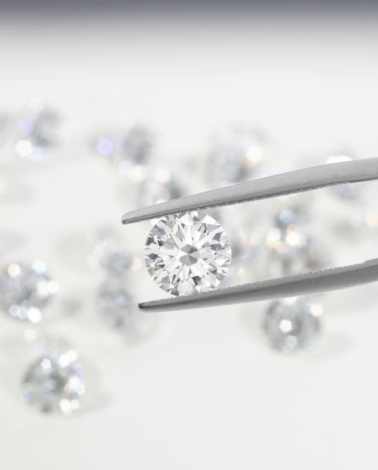 A loose round diamond being held between tweezers