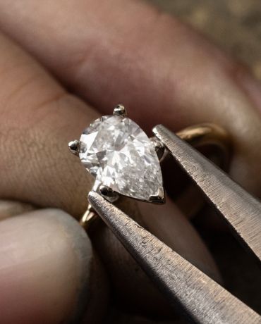 A jeweler setting a pear shaped diamond into an engagement ring