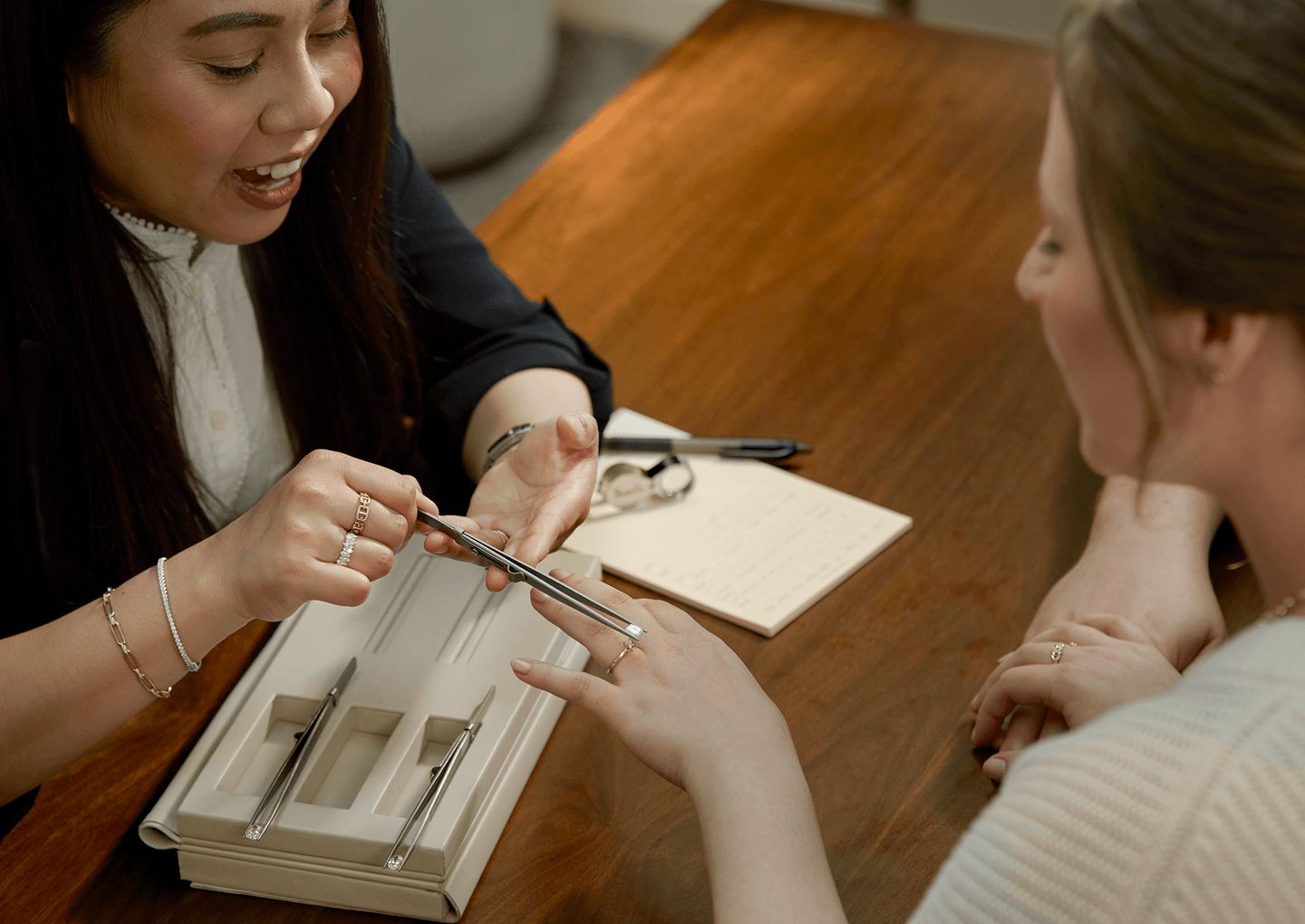 A jewelry consultant showing a customer what a diamond center stone will look like in an engagement ring setting