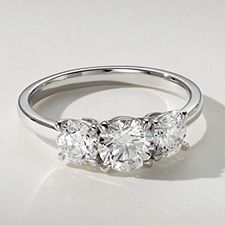 A three stone diamond engagement ring with a round center stone