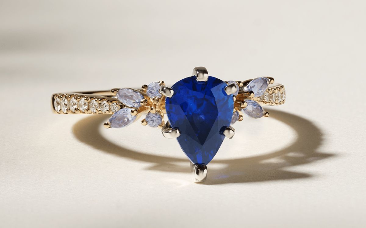 A nature inspired engagement ring with a colored pear center stone