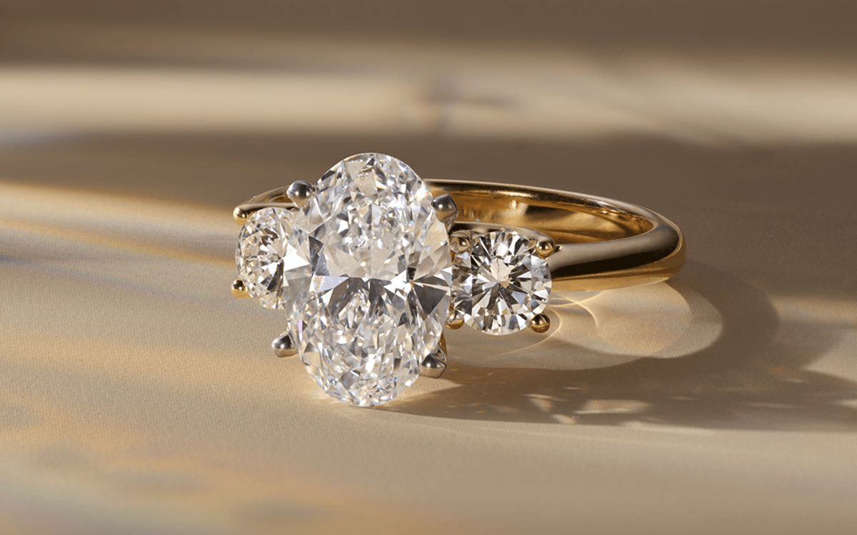 A three stone diamond engagement ring with an oval center stone