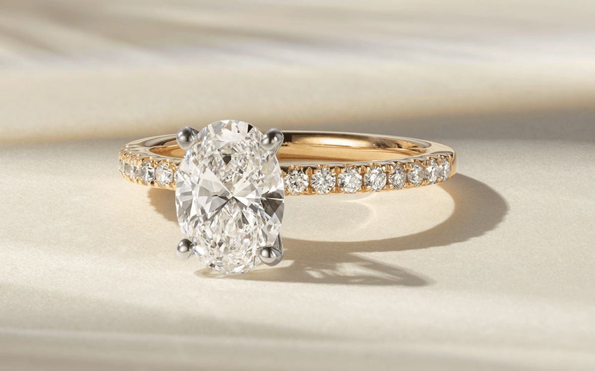 A pave-set diamond engagement ring with an oval center stone
