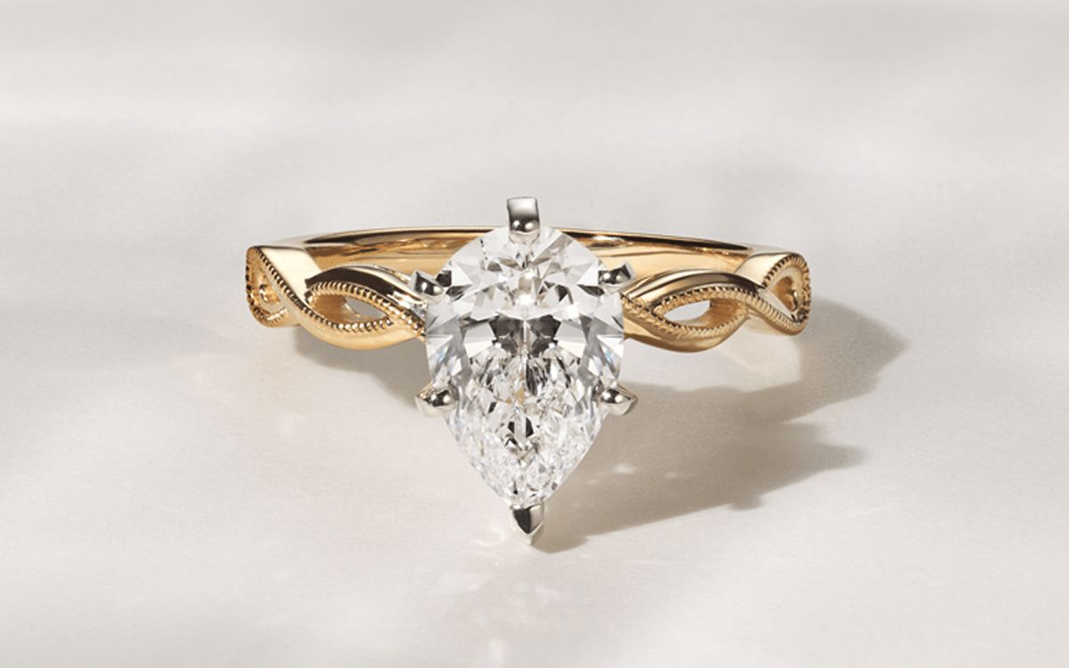 An infinity engagement ring with a pear center stone