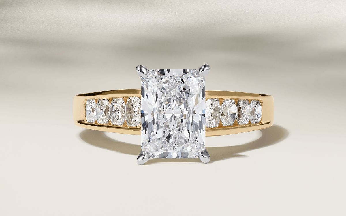 A channel set diamond engagement ring with an emerald cut center stone
