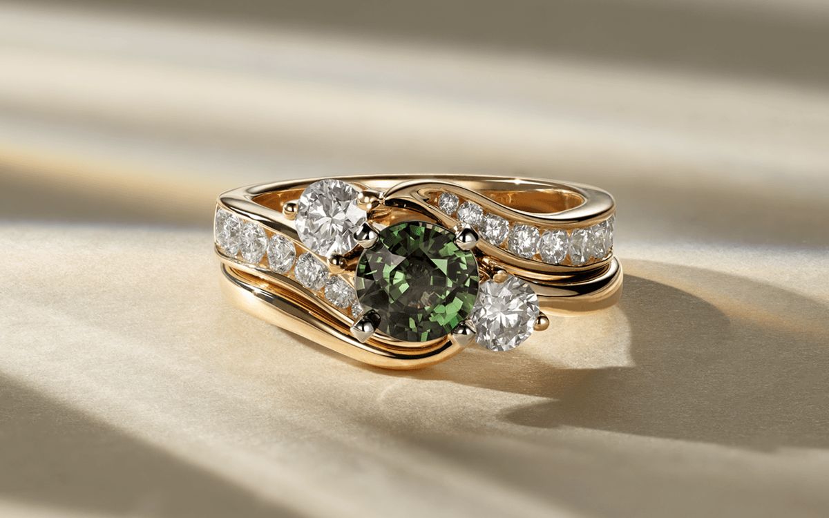 A swirl diamond engagement ring with a green sapphire center stone