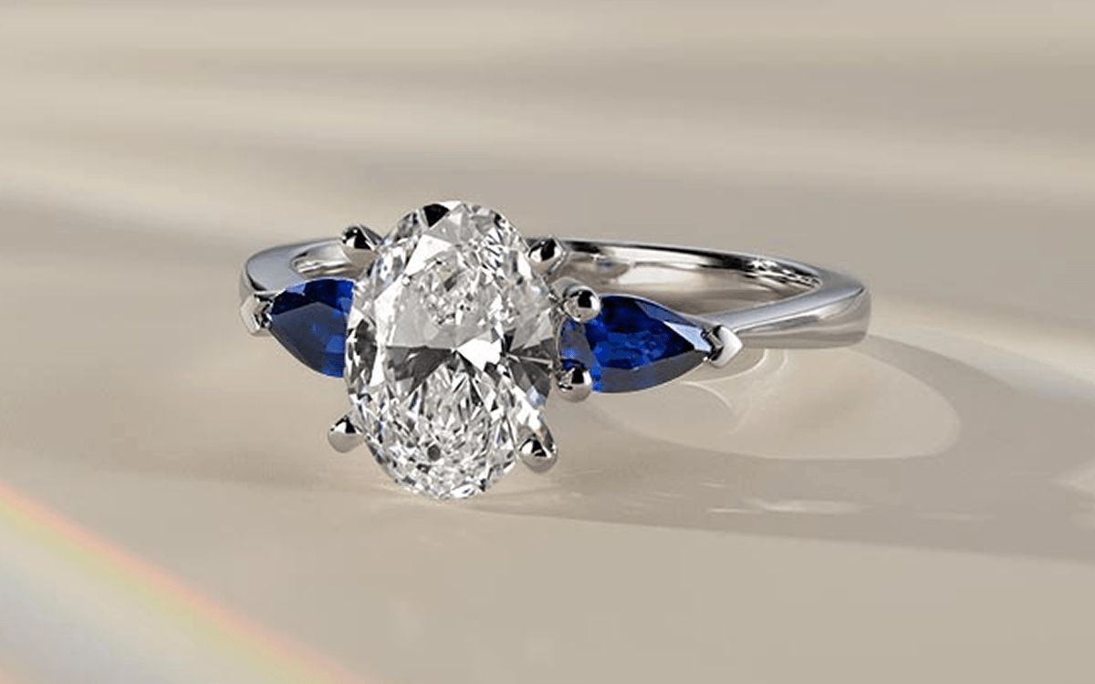 A three stone color accent engagement ring with an oval center stone