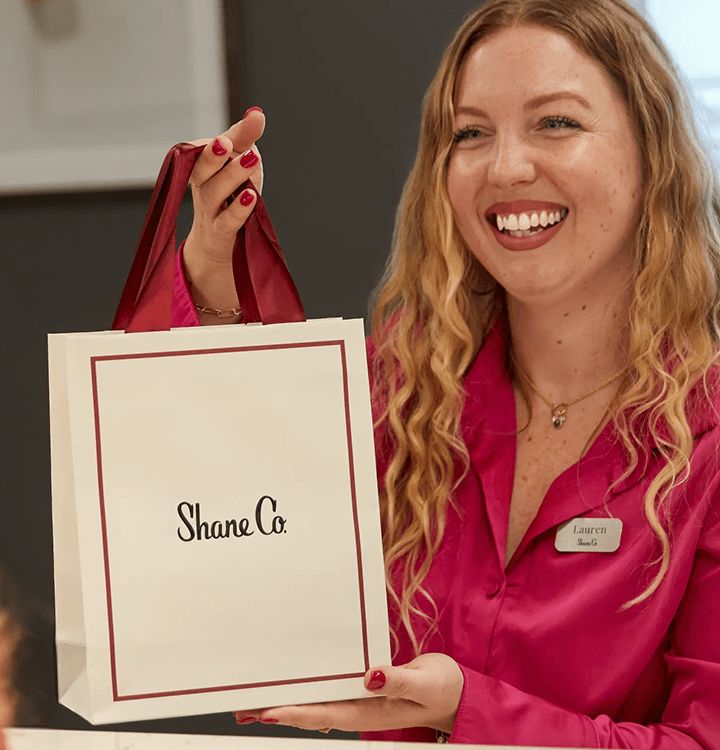 A jewelry consultant holding a Shane Co. gift bag