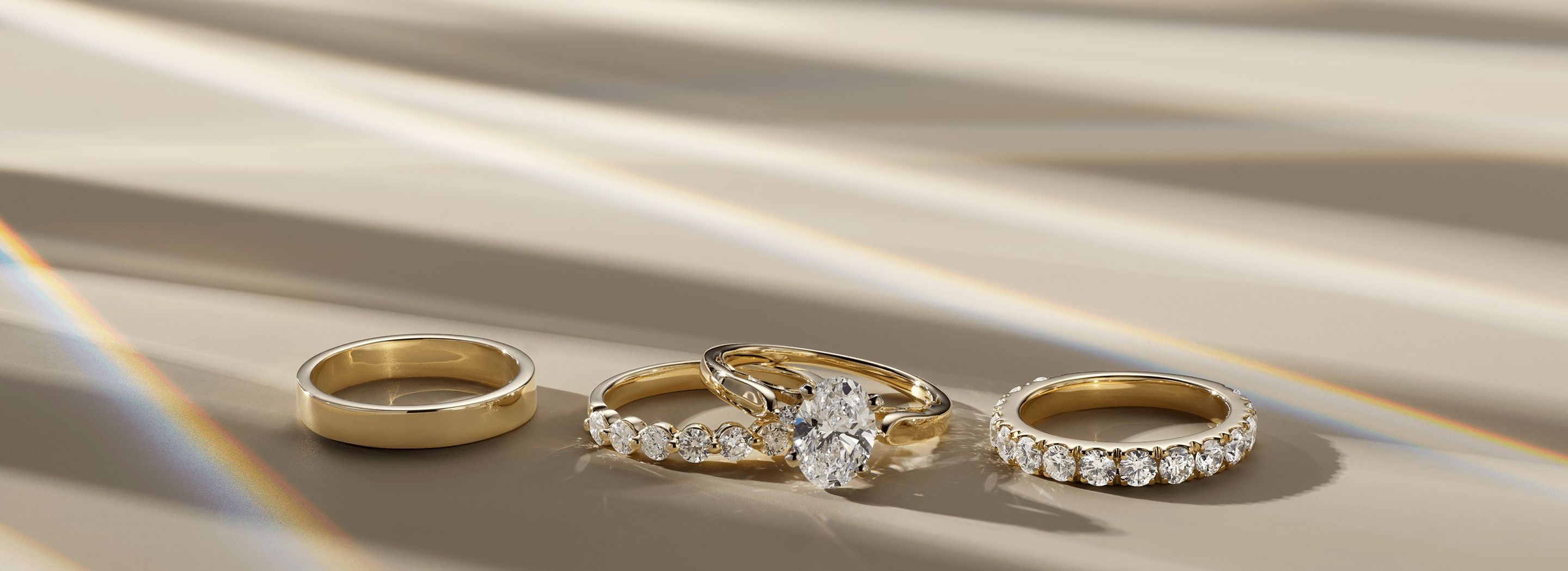 A plain wedding band, a diamond engagement ring wedding set and a diamond wedding band all sitting next to each other