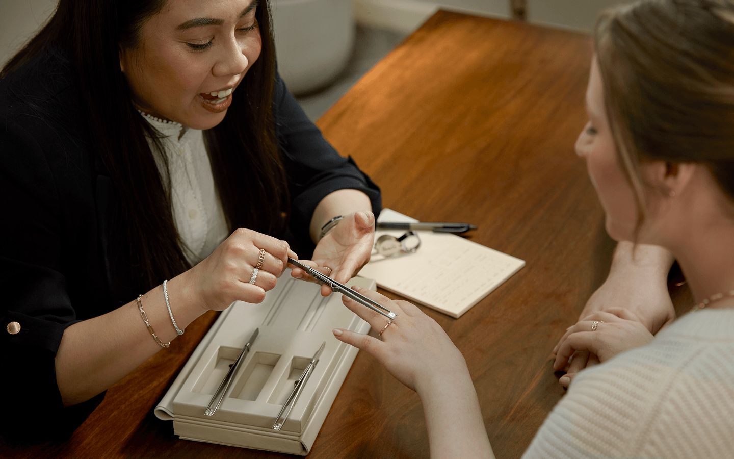 A jewelry consultant showing a customer how a loose diamond will look in their engagement ring setting