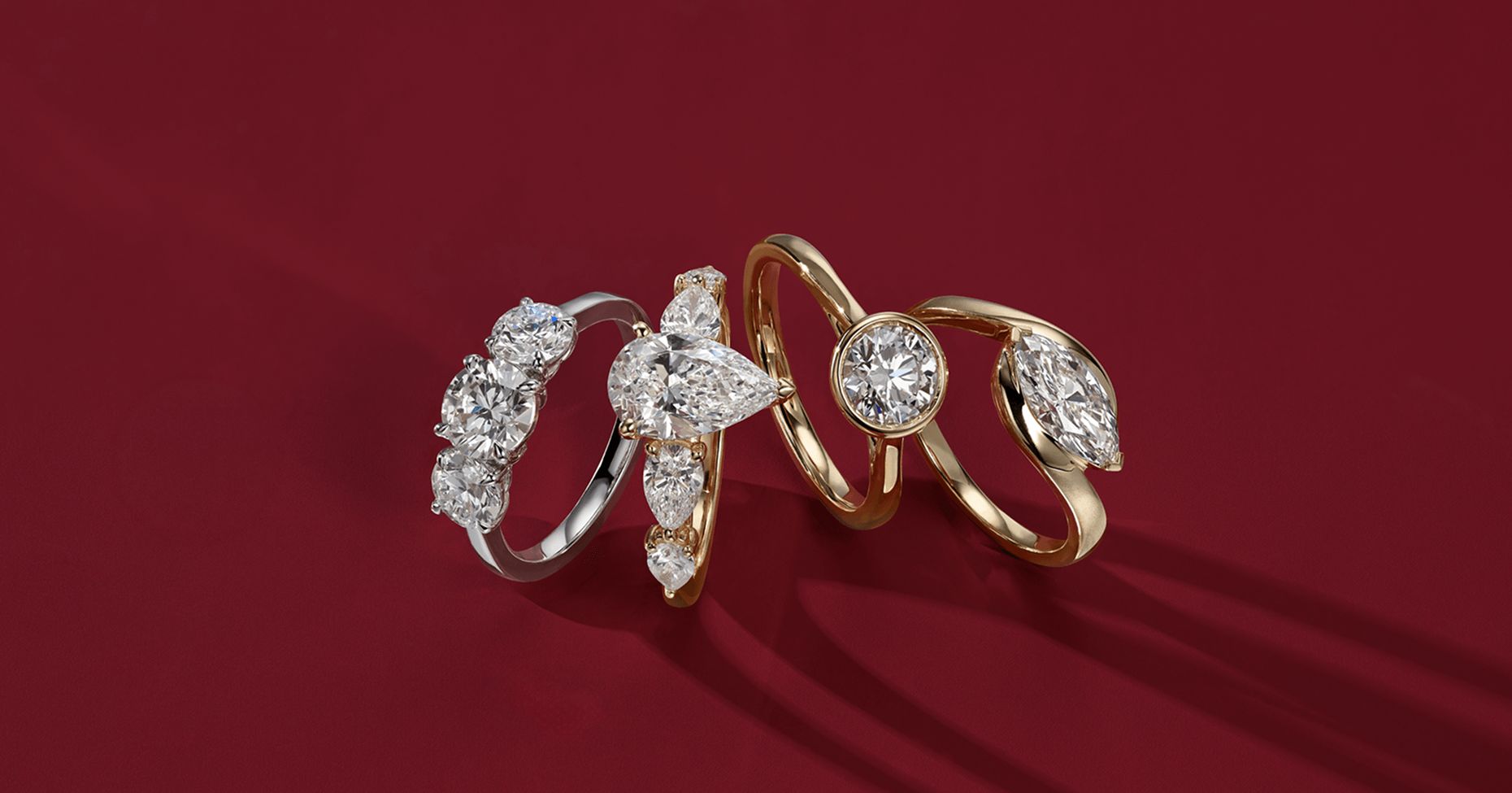 4 diamond engagement rings standing next to each other on a red background