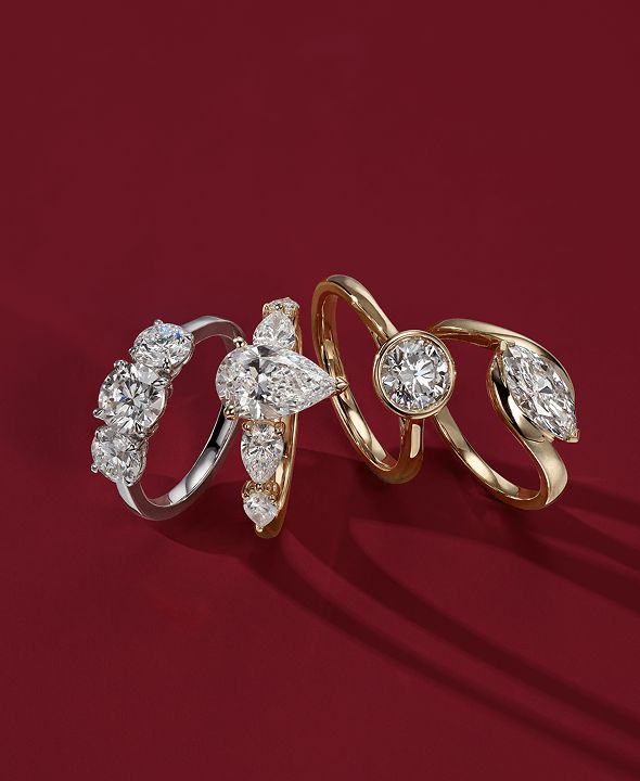 4 diamond engagement rings standing next to each other on a red background