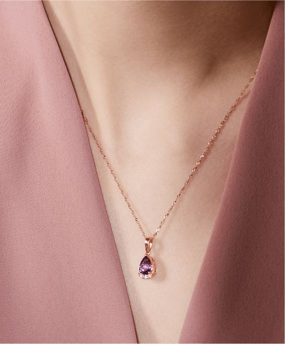 A woman wearing a gemstone and diamond pendant necklace
