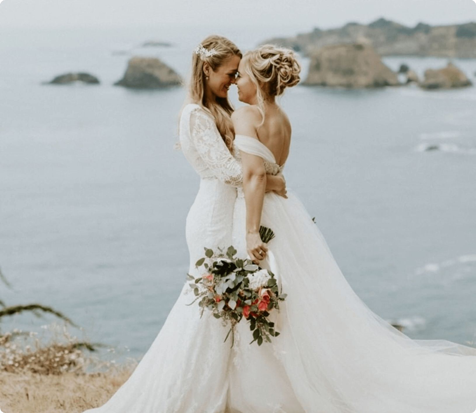 Two brides embracing each other on a cliff side