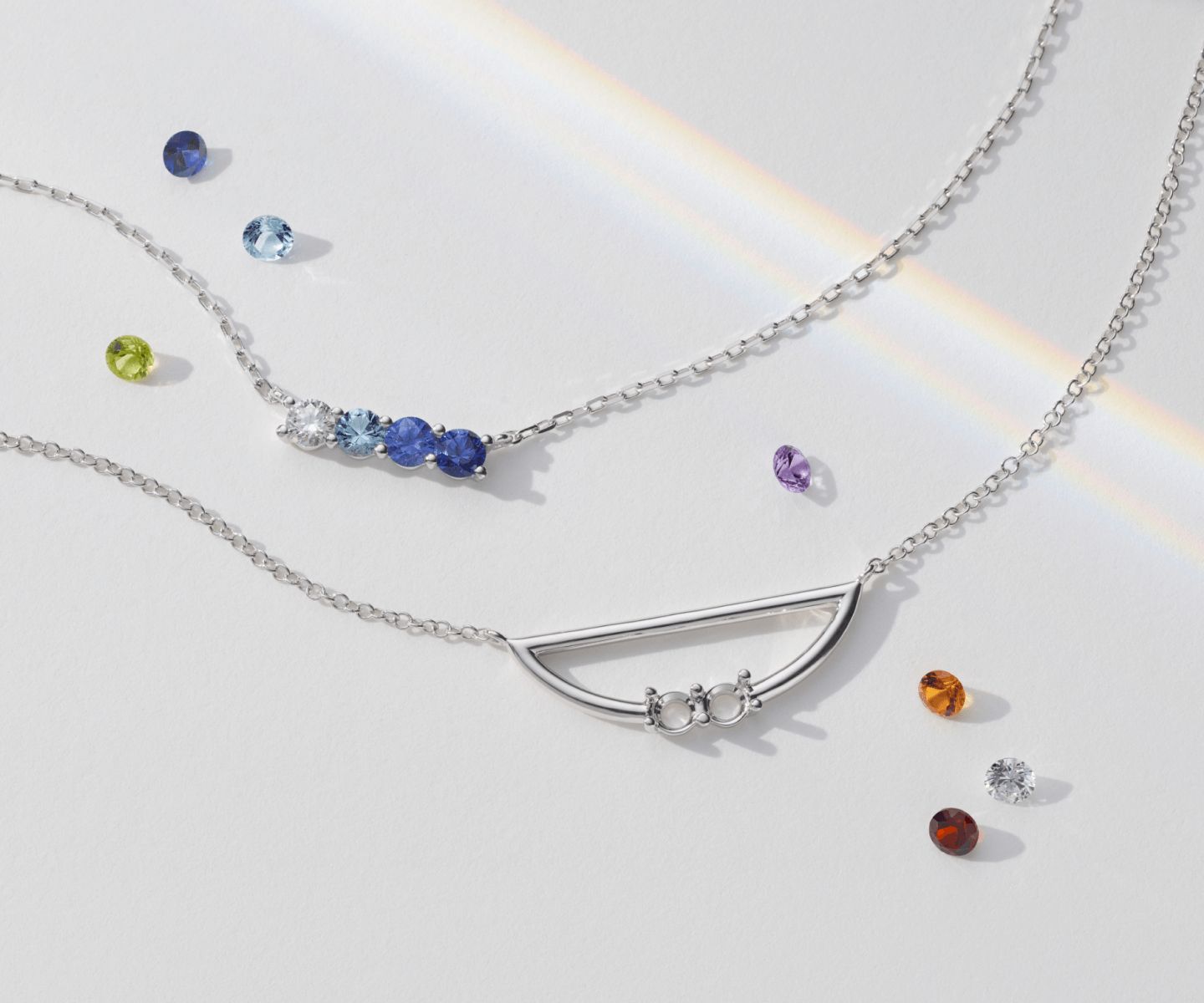 A collection of gemstone necklaces surrounded by loose colored gemstones